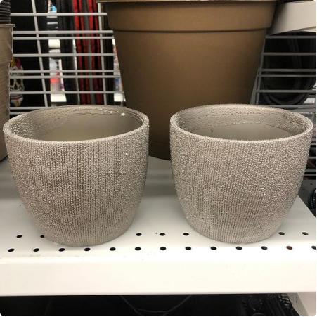 Two large gray plant pots are shown in a dd's store