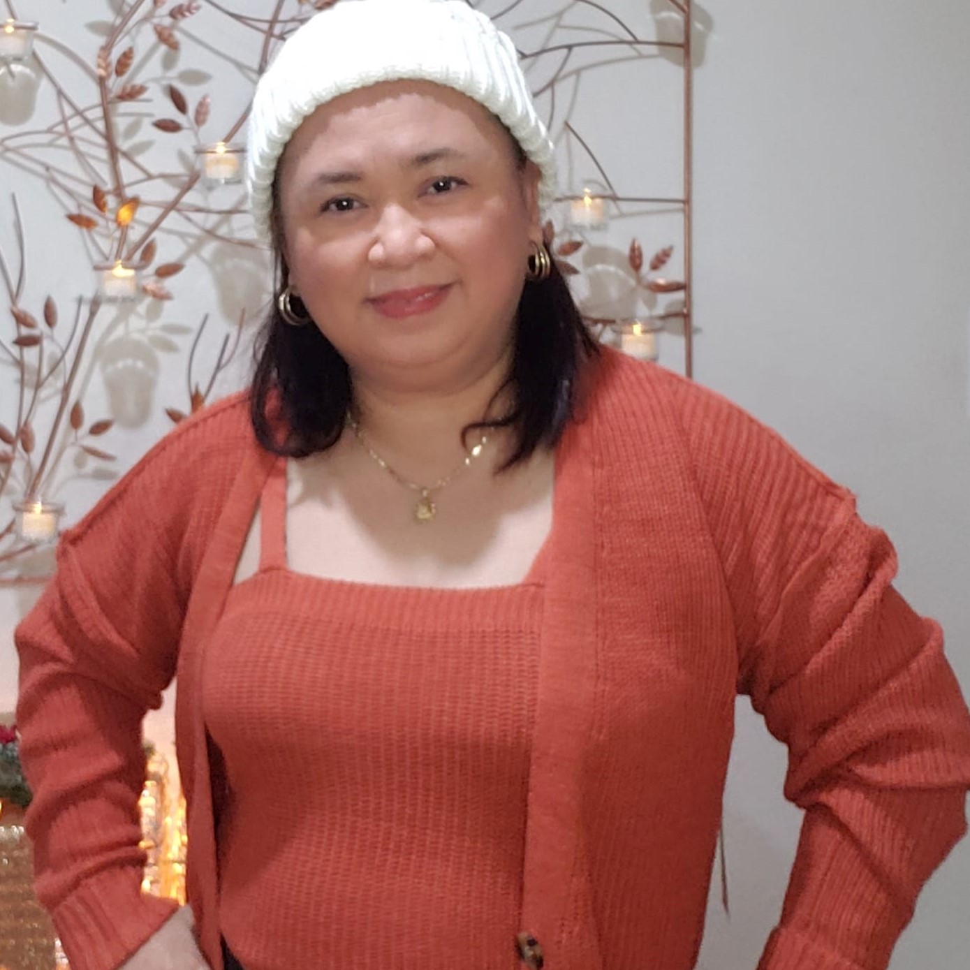 Woman is dressed in a stylish two piece outfit: a winter top, a cardigan, and a cute white hat