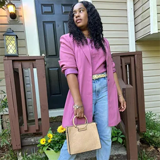 A female wearing a beautiful pink jacket and a pink top, blue jeans and a trendy hand bag from a dd's tore